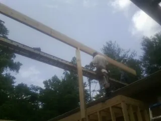 Carpenter setting a ridge beam over a new addition frame — Ice Dam Removal by Roofing Brothers in Belspring