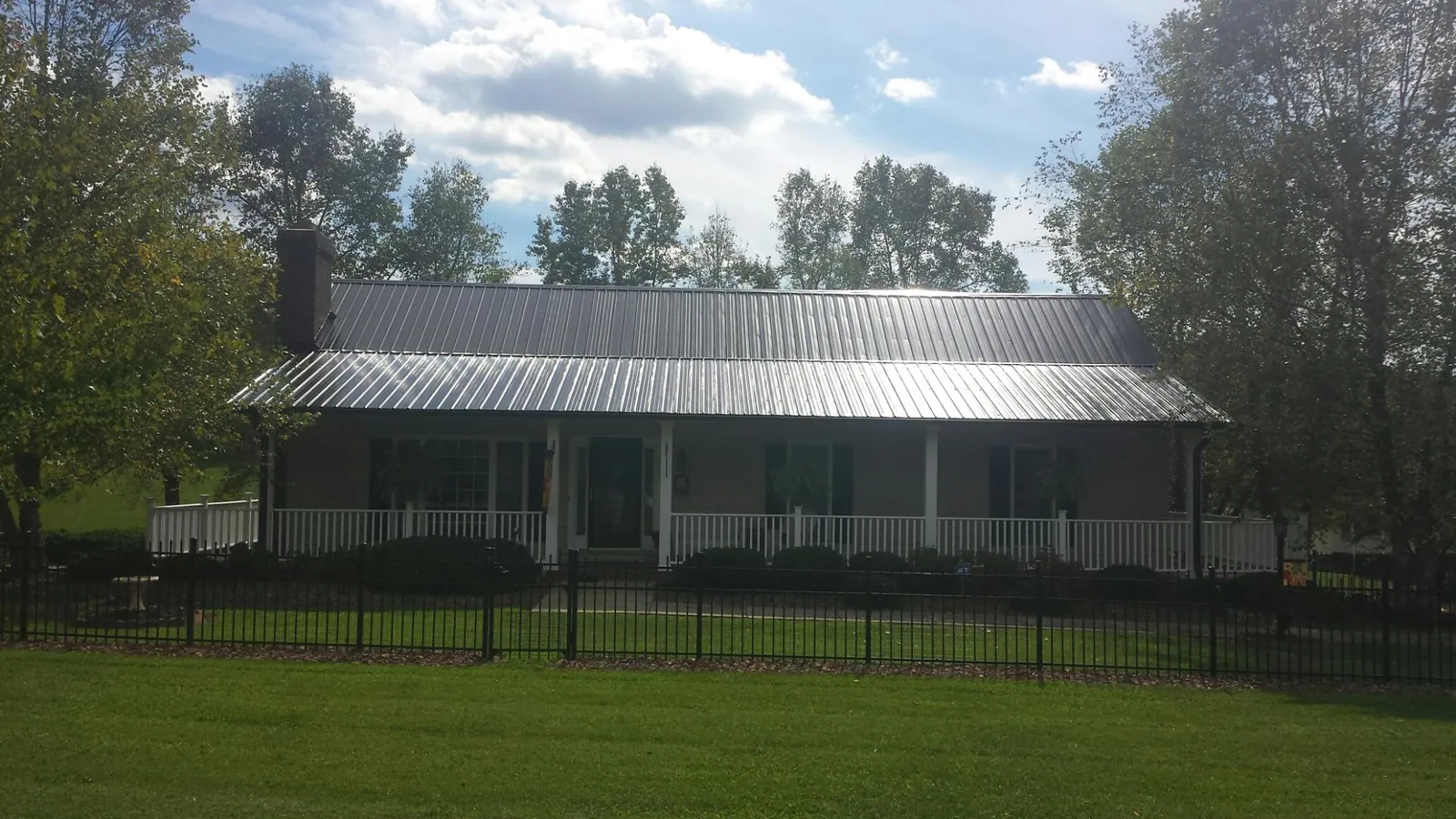 Gray metal roof on a brick ranch with a full width front porch — Gutter Guard Installation work by our crew in Belspring